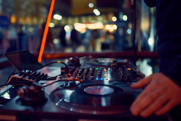 turntable, hand of dj on the vinyl record at night club. blured background