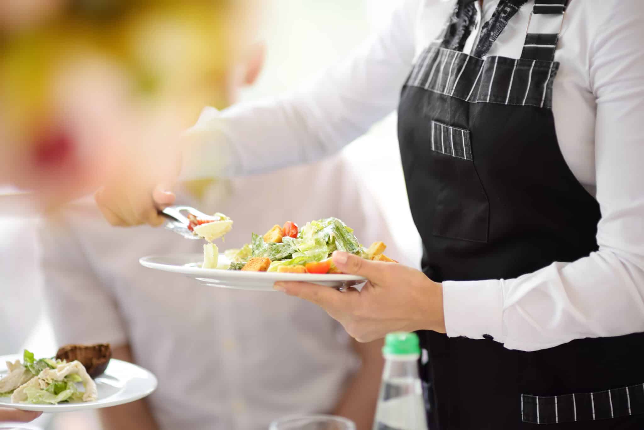 Waiter carrying plates with salad on some festive event, party or wedding reception