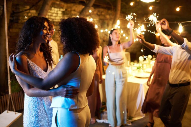 Two young amorous intercultural women in white wedding attire dancing